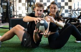 fitness center with a man and woman passing a weighted ball