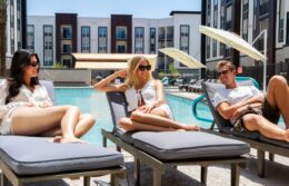 Men and women sitting in lounge chairs by the pool